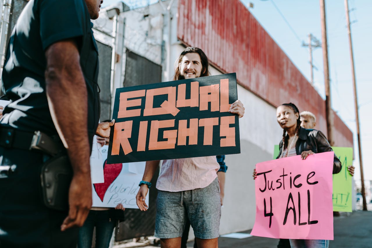 A diverse group of people holding protest signs advocating for equality and justice outdoors.